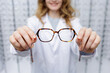 © st.kolesnikov - Optician presenting eyeglass frames to customer during prescription eyewear consultation