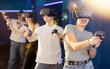 © JackF - girl in virtual reality glasses and with joystick plays exciting shooter game with friends. Technology simulation hi-tech videogame concept
