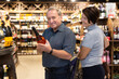 © caftor - Mature couple choosing nice bottle of champagne in supermarket