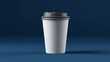 © MDALI - A minimalist studio photograph depicts a tall, smooth, logo-free white disposable paper coffee cup with a dark gray plastic lid. It is centered against a deep blue background on a flat surface.