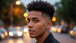 © photoplotnikov - Young african male with stylish haircut posing on city street with evening lights