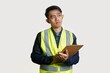 © yashis007 - Pensive Engineer in Safety Vest Looking Up While Holding Clipboard