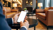 © Andika - Hand holding a smartphone with blank screen in a cozy cafe lounge environment, perfect for lifestyle branding, mobile app advertising, and social media concepts.