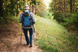 © inesbazdar - Rear view of senior hiker walking along mountain footpath with hiking poles and enjoying outdoor adventure while exploring nature.