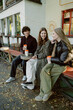 © m-art - Three friends share smiles and stories while sipping warm drinks outside a charming cafe. Golden leaves fall around them, creating a cozy atmosphere during the crisp autumn day.