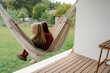 © m-art - Enjoying a serene afternoon, two friends sit close together in a hammock, surrounded by lush greenery and a peaceful garden. Their laughter fills the air as they relax.