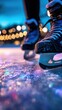 © Udin - Close-up of blue ice skates on a glittering rink with warm bokeh lights in the distant background of blue ice