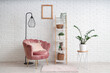 © Pixel-Shot - Interior of modern room with comfortable armchair, shelving unit and houseplants near white brick wall