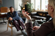 © TrueFrame Collective - Elderly Caucasian woman gesturing while conducting therapy session with young Black woman sitting and listening in modern office setting, focus on therapist hand movement