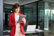 © Stock 4 You - 40s mature ceo professional business leader executive woman standing in office at work working on tablet computer. Happy hispanic middle aged businesswoman using touchpad pc at workplace. Copy space