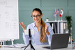© Prostock-studio - A happy English teacher is recording a vlog from her home office. She gestures to the camera while teaching online, demonstrating techniques for engaging with students during social distancing.