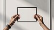 © ghulab - Hands holding empty picture frame against minimal modern wall
