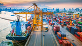 Cargo ship loading and unloading at a busy commercial port at sunset