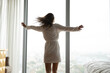 © fizkes - Overjoyed with freedom. Back view carefree millennial woman with slim figure spinning around in bedroom with large picture window admire spectacular city view enjoy fresh daylight in luxury apartment