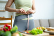 © Nuttapong punna - Weight loss and fitness concept of woman measuring waist at home. Healthy lifestyle, diet plan, body measurement, nutrition and wellness routine