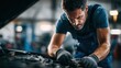 © Kate - auto mechanic repairing car engine in professional garage workshop, focused male technician performing engine maintenance and inspection