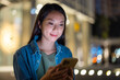 © leungchopan - Woman using cellphone in city at night