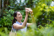 © leungchopan - Woman taking photo with phone in forest
