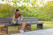 © leungchopan - Mother wiping baby hands while sitting on park bench