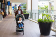 © leungchopan - Mum pushing baby stroller walking in shopping center