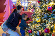 © leungchopan - Mother holding baby while watching christmas tree indoors