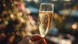 © Natalia Klenova - Hand Holding Champagne Glass with Bubbles and Festive Bokeh