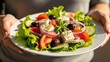 © Tatiana - Woman holding plate with fresh greek salad. Healthy eating and mediterranean cuisine, concept for cooking recipe and diet.