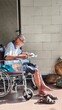 © Creativa Images - Elderly Asian Man in Wheelchair Reading Newspaper in Sunlight