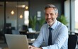© Oliver - Busy happy middle aged business man company manager investor working online on computer sitting at office desk. Mature older professional businessman executive using laptop at corporate workplace.
