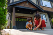 © unai - Mother and son playing with toy cars in front of house
