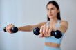 © we.bond.creations - Young woman actively training with black dumbbells, staying fit and promoting a healthy lifestyle. Focusing on strength and wellness