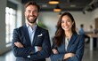 © Isabella - Triumphant cheerful male and female executives posing with folded arms and grinning at camera in workplace setting. Collaboration idea. High quality