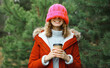 © rohappy - Winter day, happy smiling woman holding cup of coffee drink enjoys snow, against Christmas tree