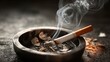 © sablengjago - A lit cigarette rests in an ashtray, smoke curling upwards against a dark backdrop. The ash tray shows cigarette remnants