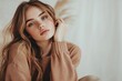 © sunshinemother - A young woman with blue eyes and long hair wears a warm sweater and rests her head on her hand gently.