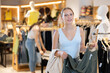 © JackF - Young woman went to a clothing store in the summer and chooses green pants. Woman buys clothes in the mass market