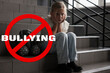 © New Africa - Stop bullying. Sad little girl with toy bunny on stairs indoors. Prohibition sign with word