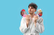 © Pixel-Shot - Sad young man in bathrobe with graying hair and color dye palettes on blue background