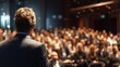 © Prapan - Leadership on Display: A poised speaker captivates a large audience, delivering a presentation in a grand auditorium, inspiring through oration and expertise.