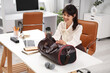 © Pixel-Shot - Young businesswoman with water bottle and sports bag at table in office