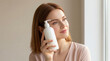 © Babla - Woman with Red Hair Holds Lotion Bottle to Her Cheek holding skincare