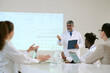 © AnnaStills - Middle aged Caucasian man presenting medical data on screen to diverse group of young adult and middle aged colleagues, including Black man and Caucasian women during meeting