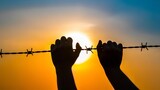 Silhouette of hands holding barbed wire against an orange and blue sky during a vibrant sunset, symbolizing struggle and resilience