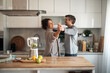 © Jelena - Couple Dancing Together in a Modern Kitchen, Enjoying a Warm Home Moment