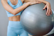 © we.bond.creations - Woman in blue sportswear preparing for an exercise routine, holding a stability ball for fitness and core strength
