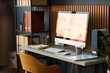 © DragonImages - Modern workspace featuring desktop computer displaying business analytics charts and graphs on screen, organized desk with office supplies, shelving unit with folders and documents in background