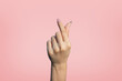 © Supachai - Korean finger heart hand gesture isolated on pink background