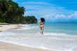 © GERMANALBERTO - Woman jogging on tropical beach by turquoise ocean, back view in bikini with palm trees, wide seascape, blue sky, summer holiday travel lifestyle, tropical beach.