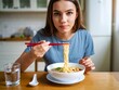 © Vision Link - Young Woman Eating Ramen Noodles with Chopsticks at Home