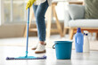 © Pixel-Shot - Young woman with plastic bucket mopping floor at home